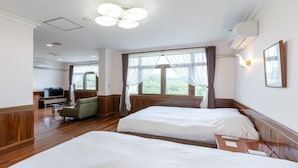 A hotel room with two beds, a TV, a sofa, and large windows with curtains.
