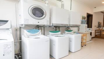 A laundry room with multiple washing machines and dryers, a wooden stool, and a water dispenser.