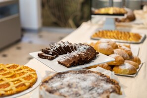 A buffet table with various desserts including a pie, a lattice-topped cake, and pastries. - Hotel Palos (Rimini)