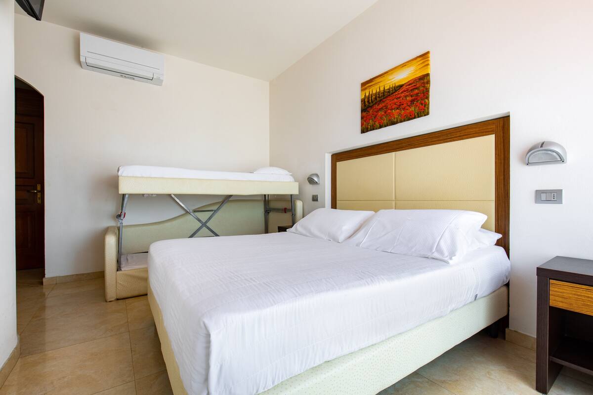 Una camera d'albergo con un letto grande, una scrivania e un quadro appeso al muro.
