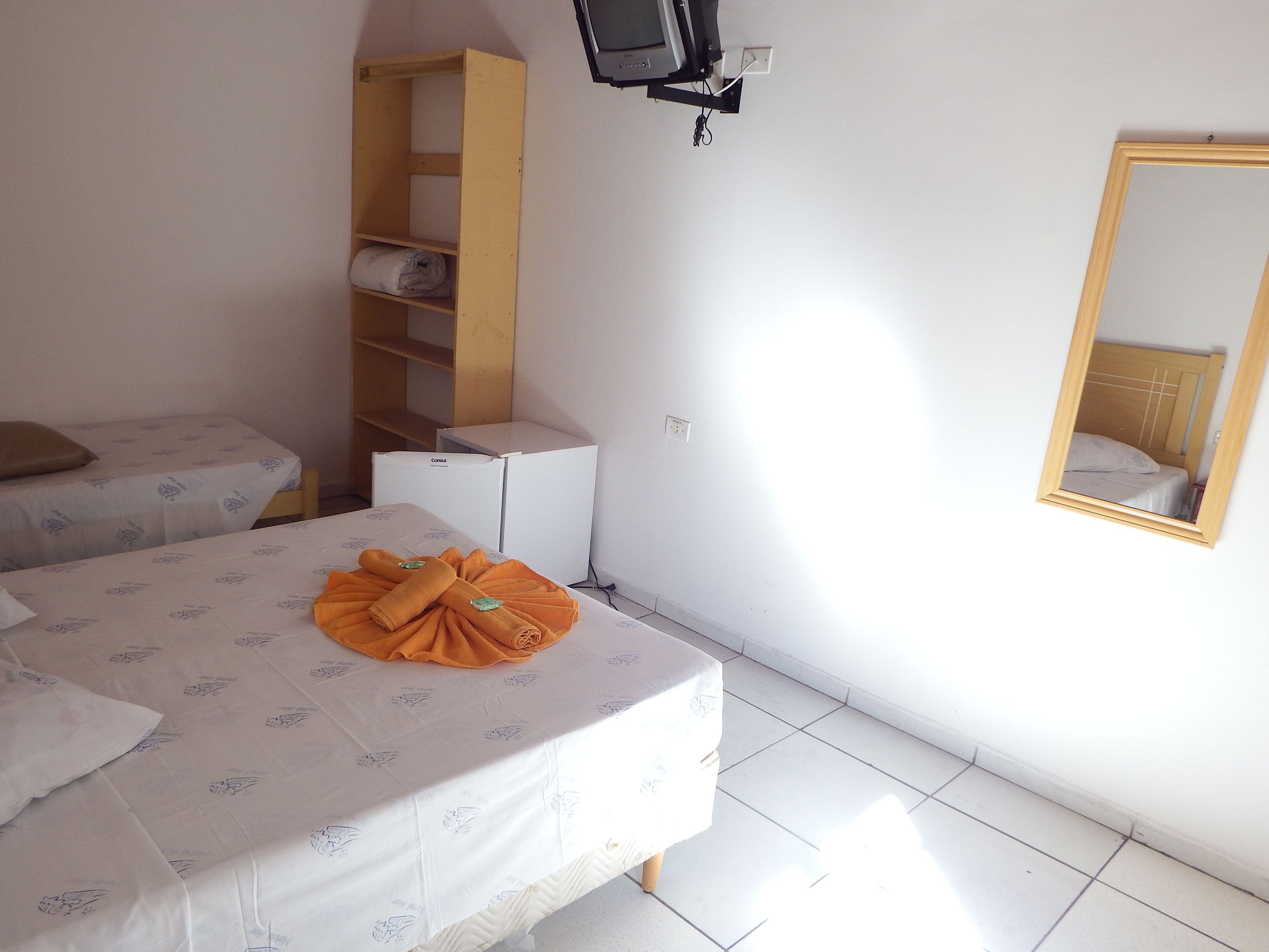 A bedroom with a bed, a wardrobe, a small desk, and a mirror.