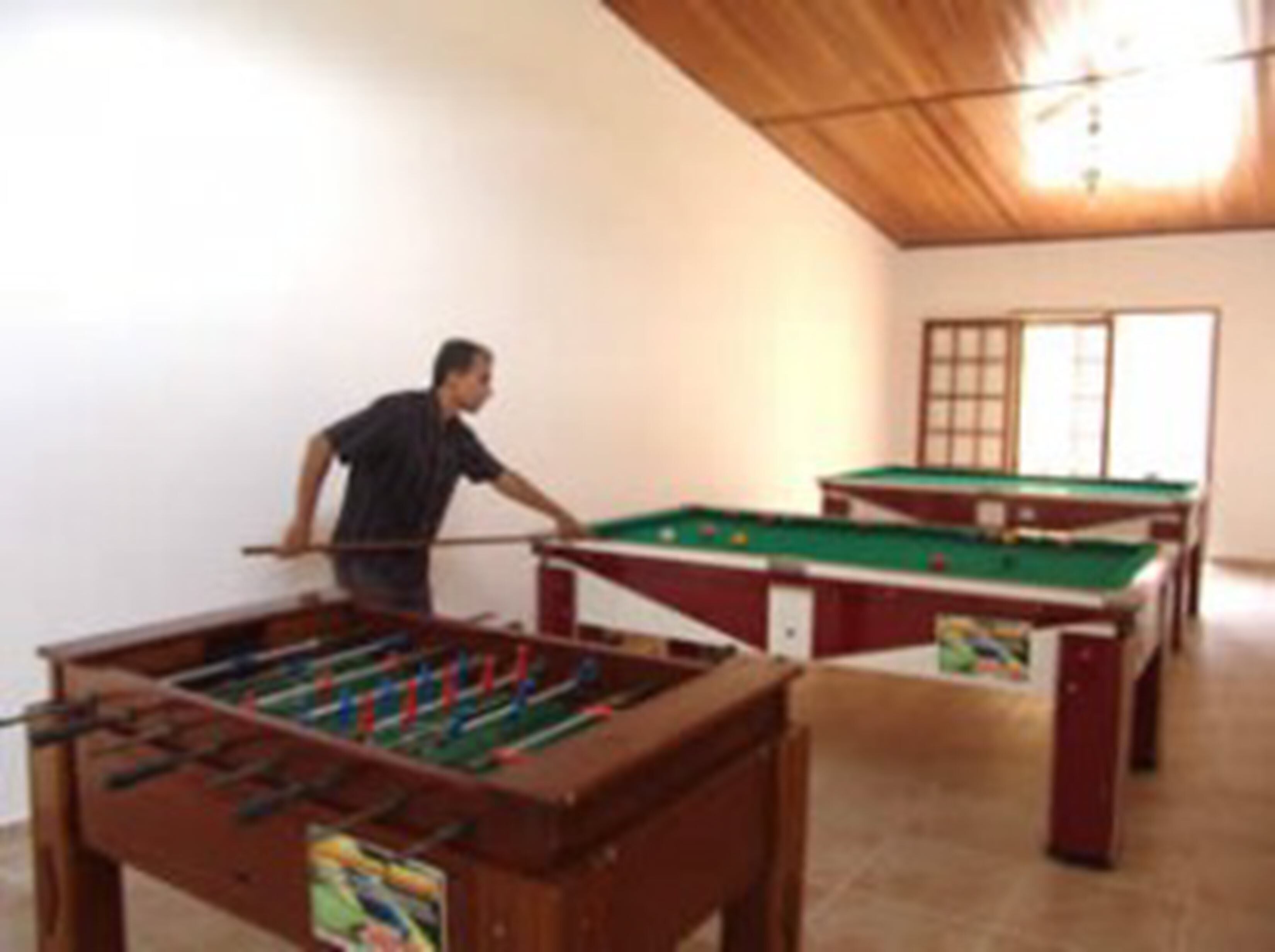 Una sala de billar con dos mesas de pool y una mesa de futbolín.