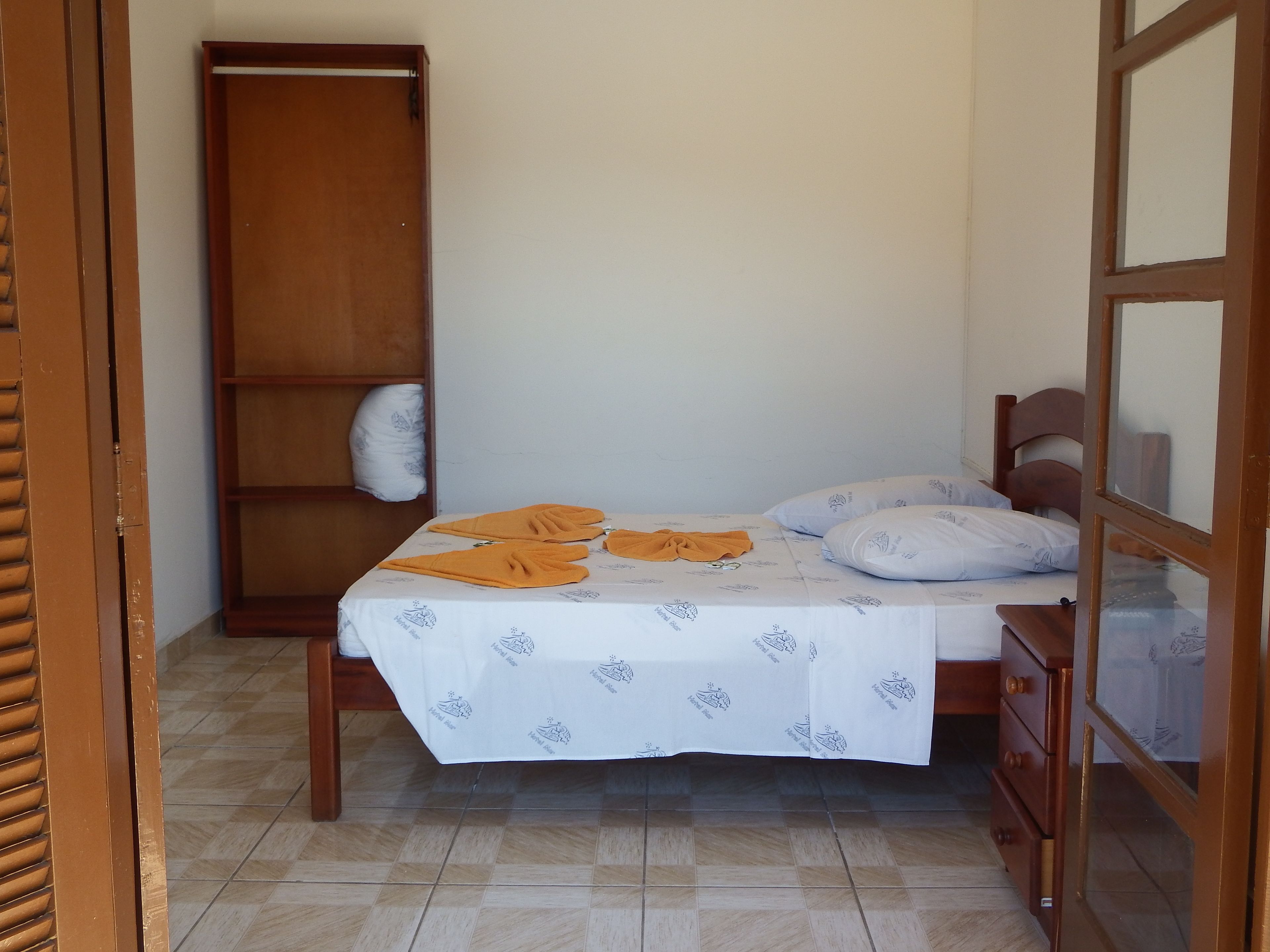 Un dormitorio con cama, un armario de madera y una mesita.
