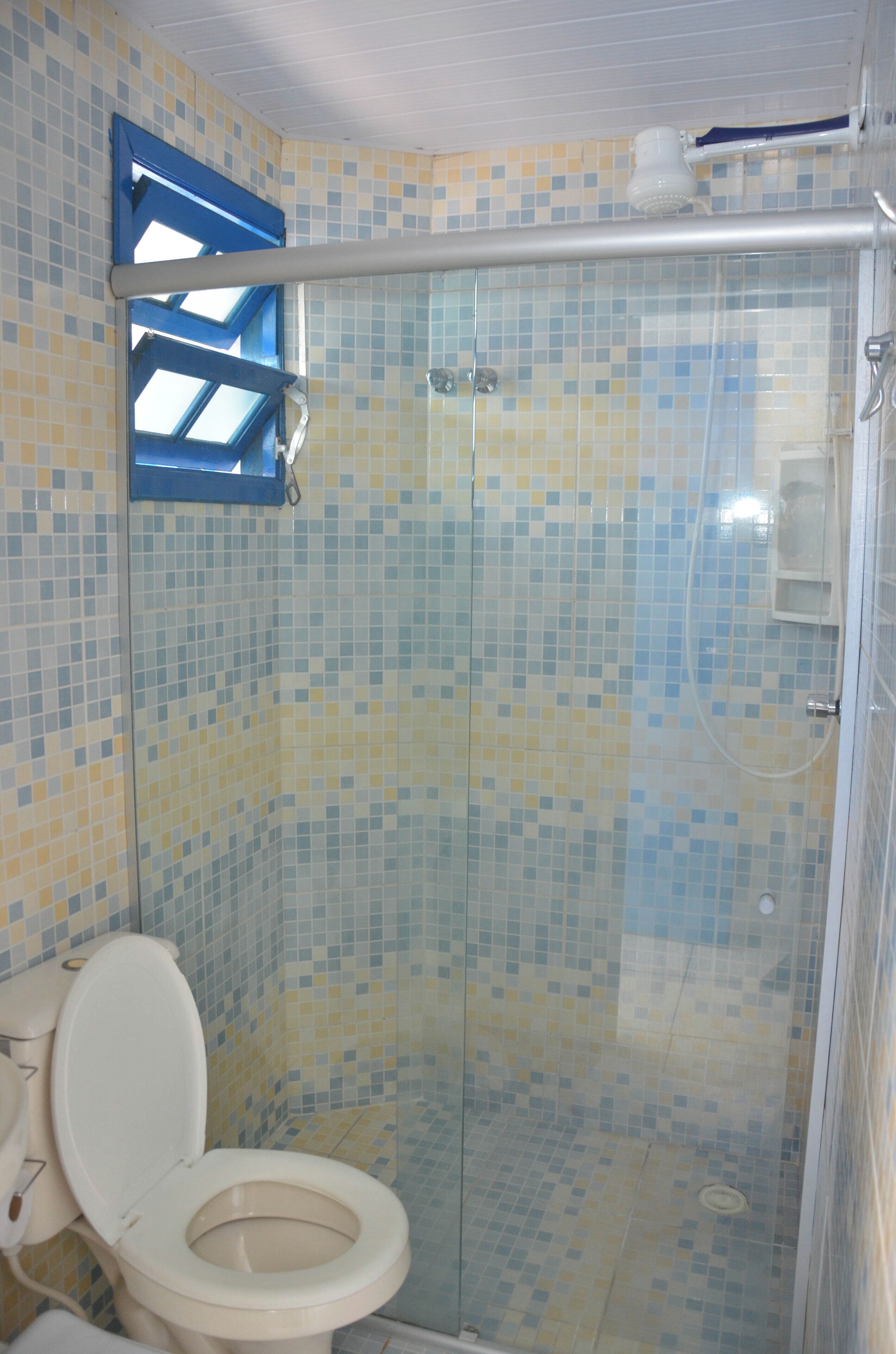 A bathroom with a tiled mosaic wall, a shower enclosure, and a toilet.
