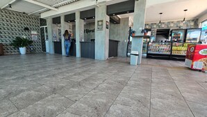 A spacious lobby with a tiled floor, a reception desk, and a vending machine area.