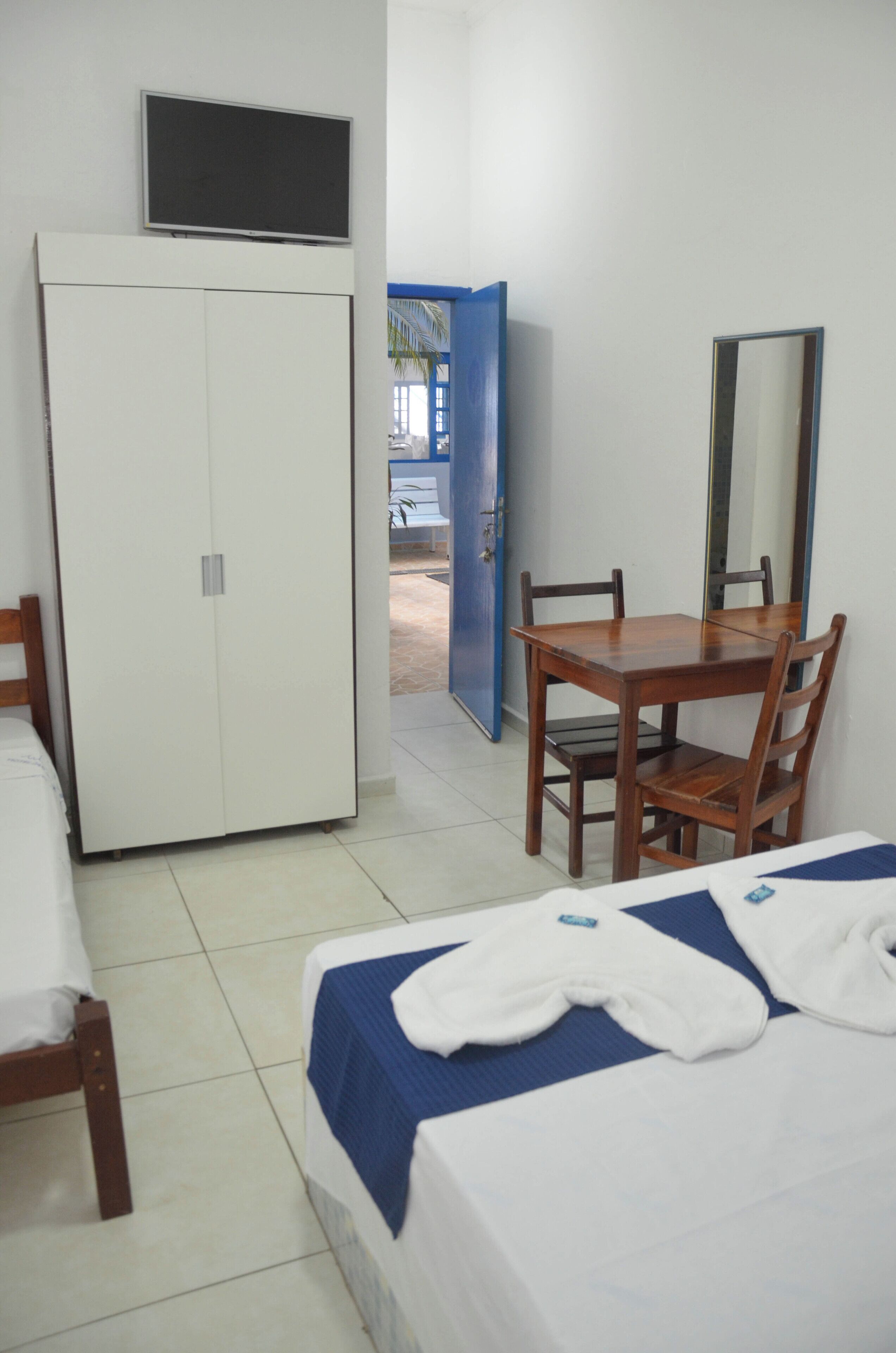 Habitación de hotel con cama, escritorio, sillas, armario, televisor y espejo.