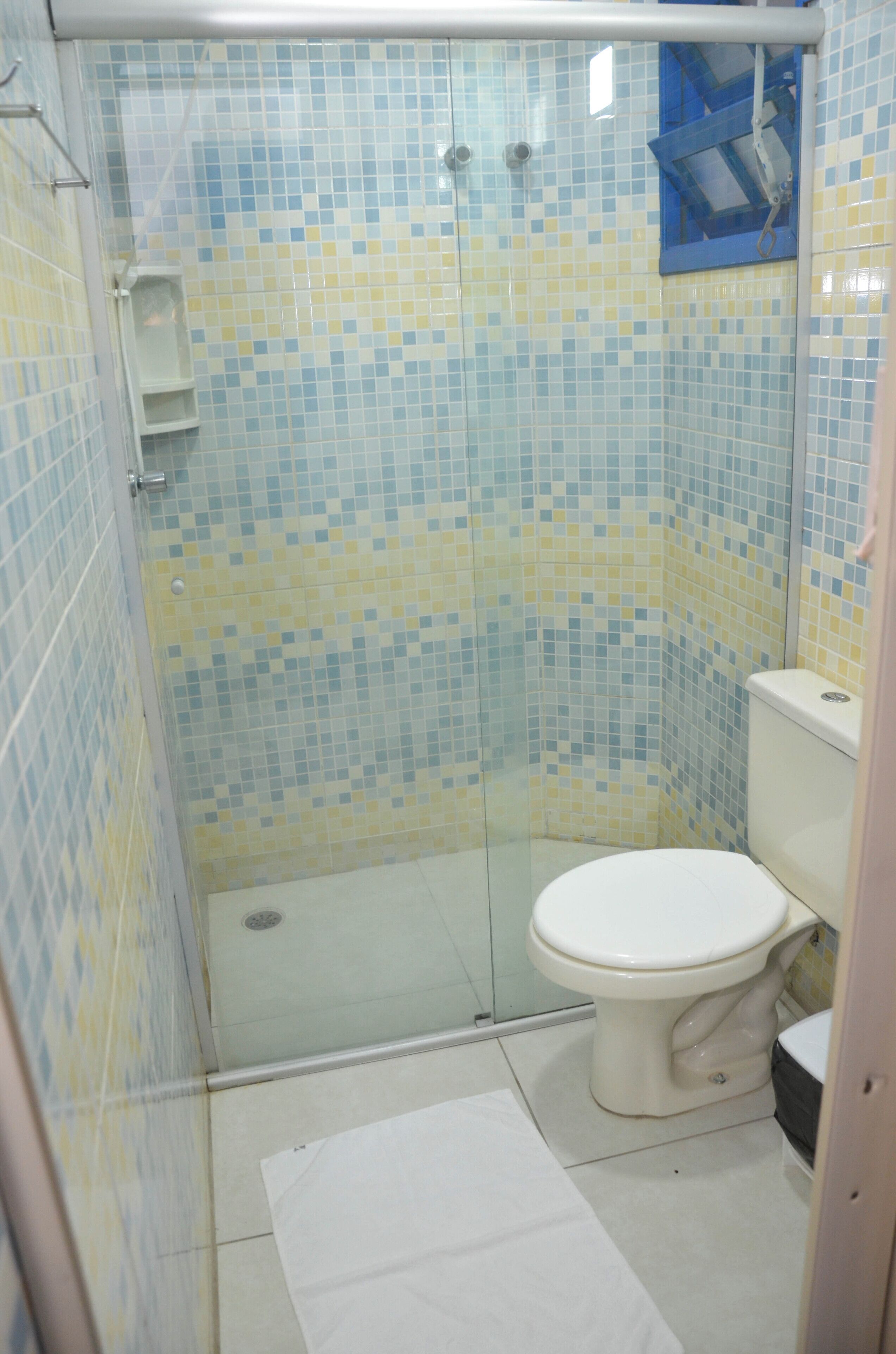 Un bagno con doccia, WC e un piccolo ripiano.