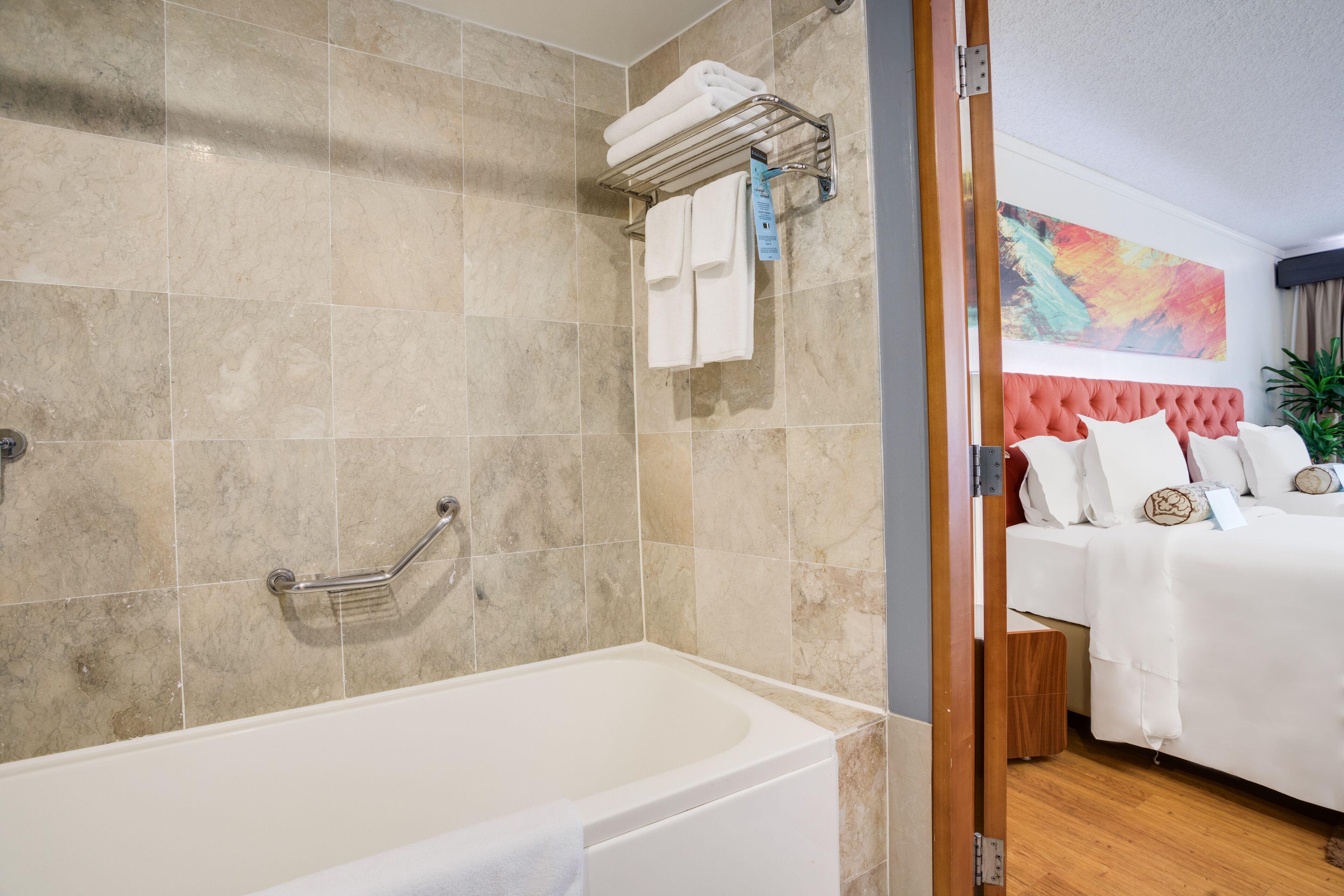 Une salle de bain moderne avec une baignoire, un porte-serviettes avec des serviettes et une douche équipée d’une barre d’appui.