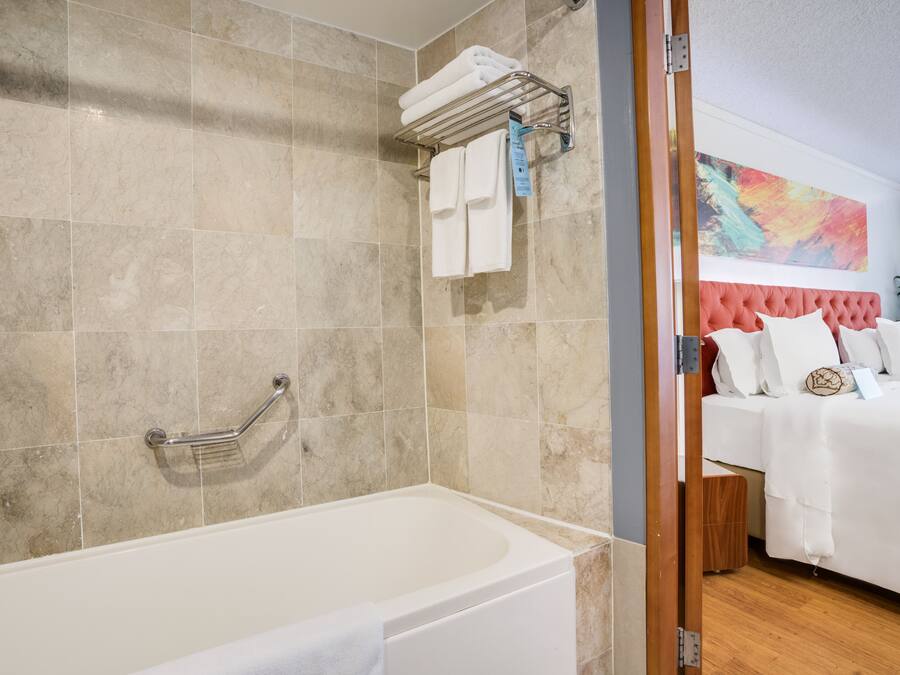 Une salle de bain moderne avec une baignoire, un porte-serviettes avec des serviettes et une douche équipée d’une barre d’appui.