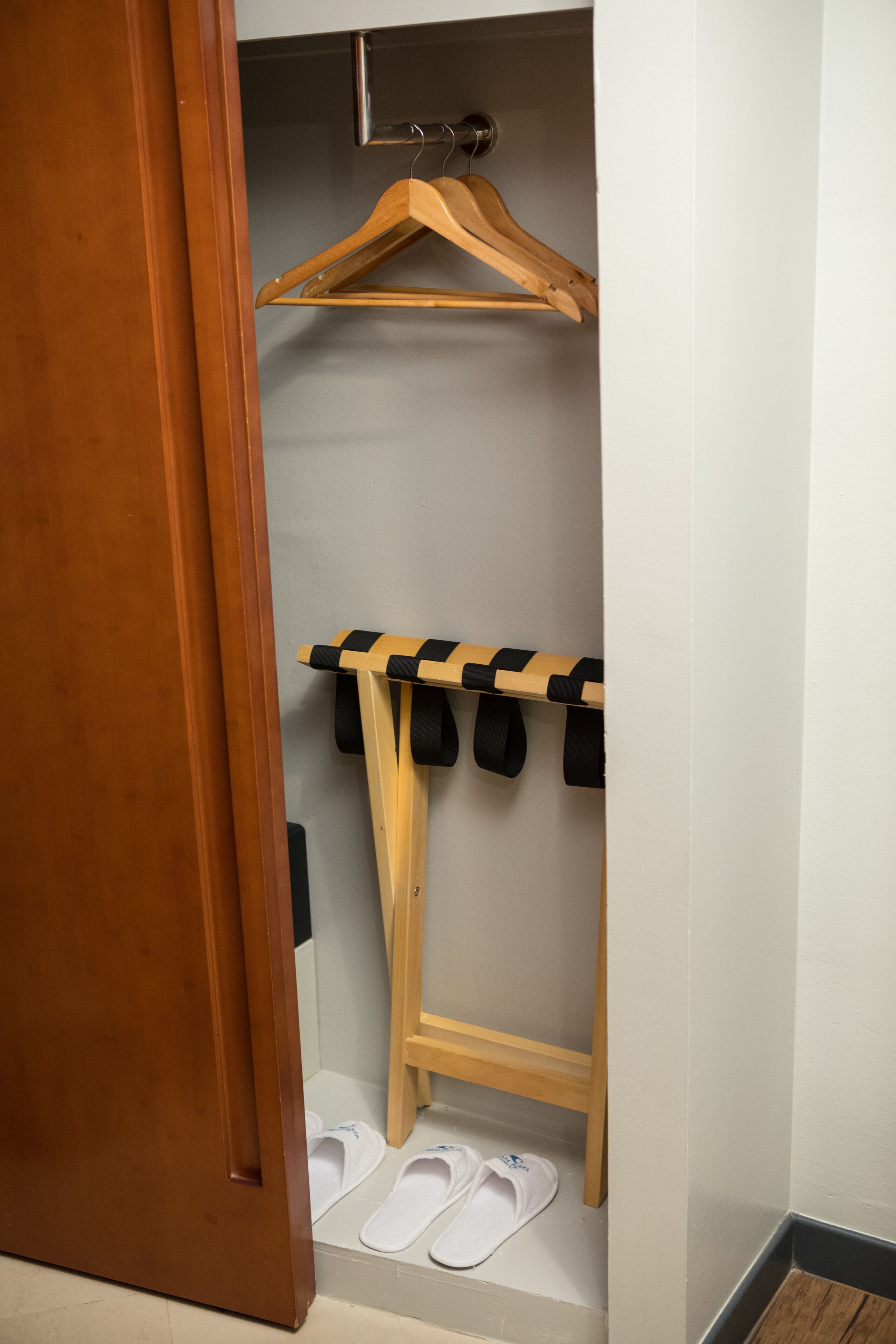 A wooden door leading to a closet with a wooden hanger and a black and white striped hanger rod.