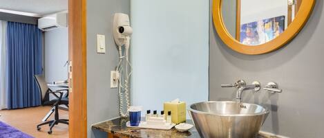 A hotel bathroom with a sink, mirror, and hairdryer.