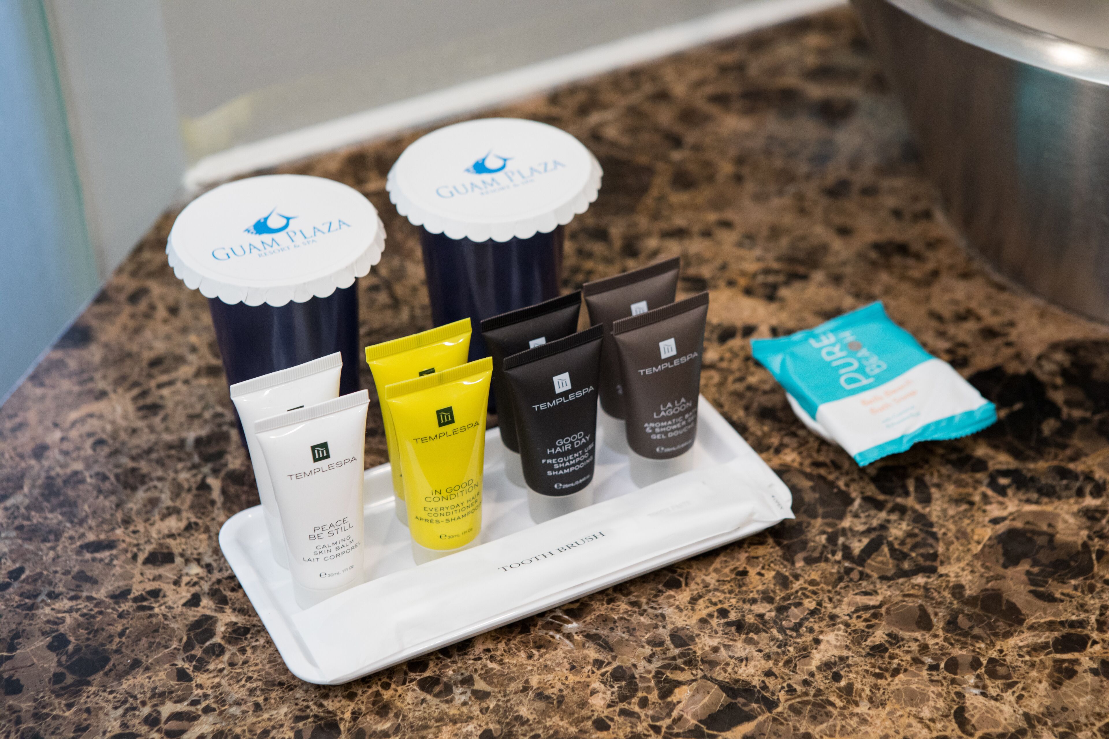 A tray with various toiletries including a toothbrush, a tube of toothpaste, and several hair care products.
