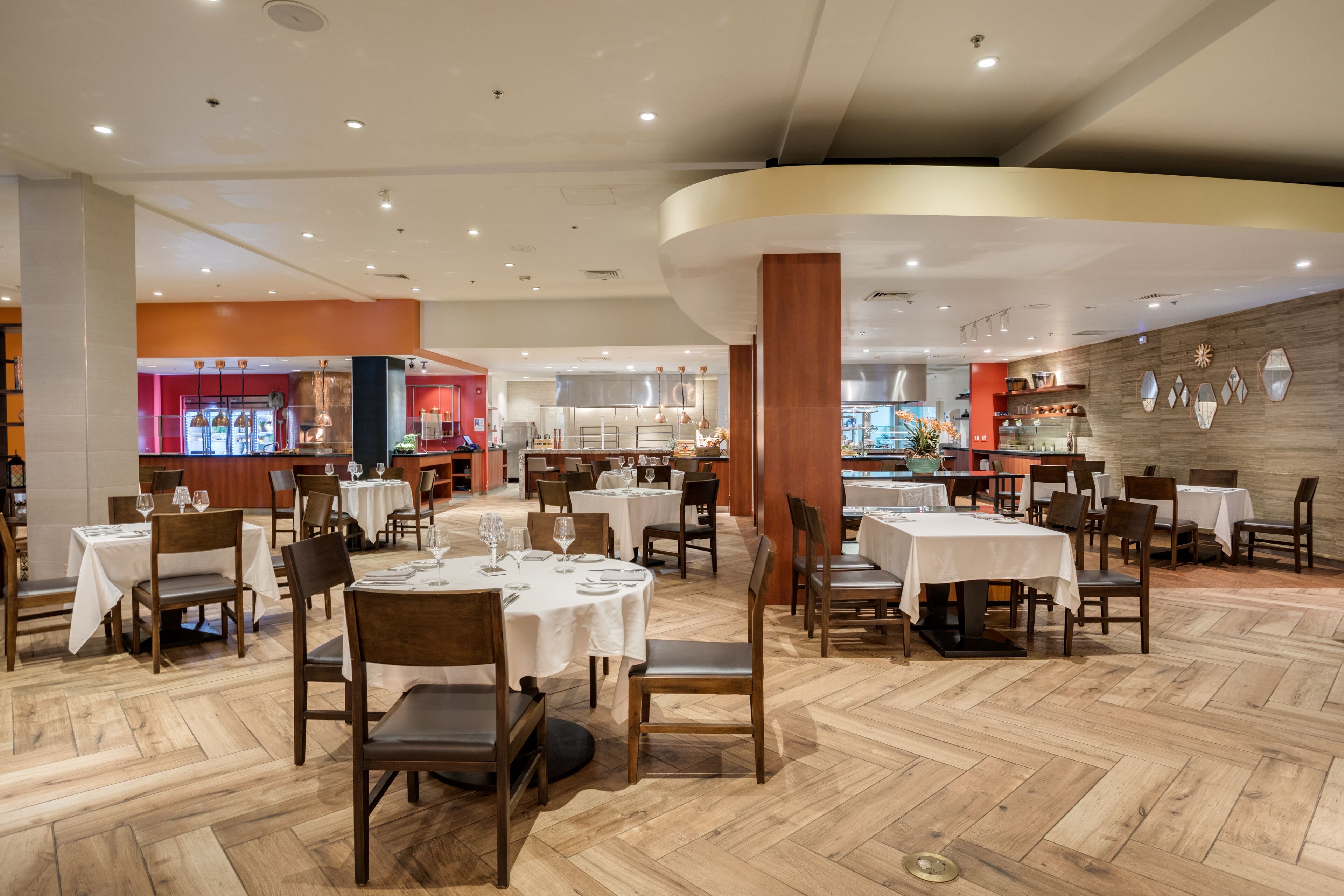 A spacious restaurant with multiple tables and chairs, a wooden floor, and a modern interior design.