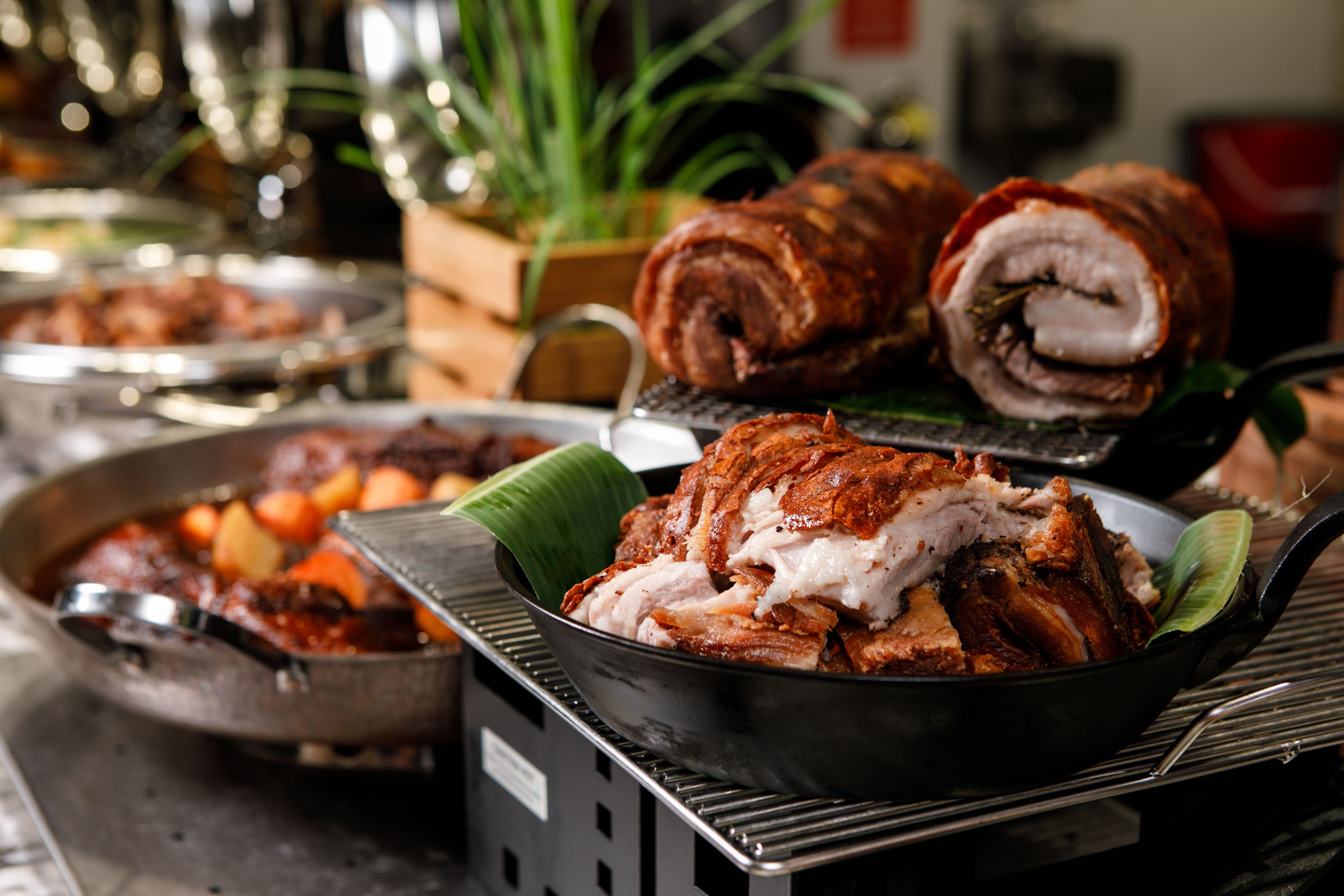 A buffet with various dishes, including a rolled meat dish and a bowl of stew.