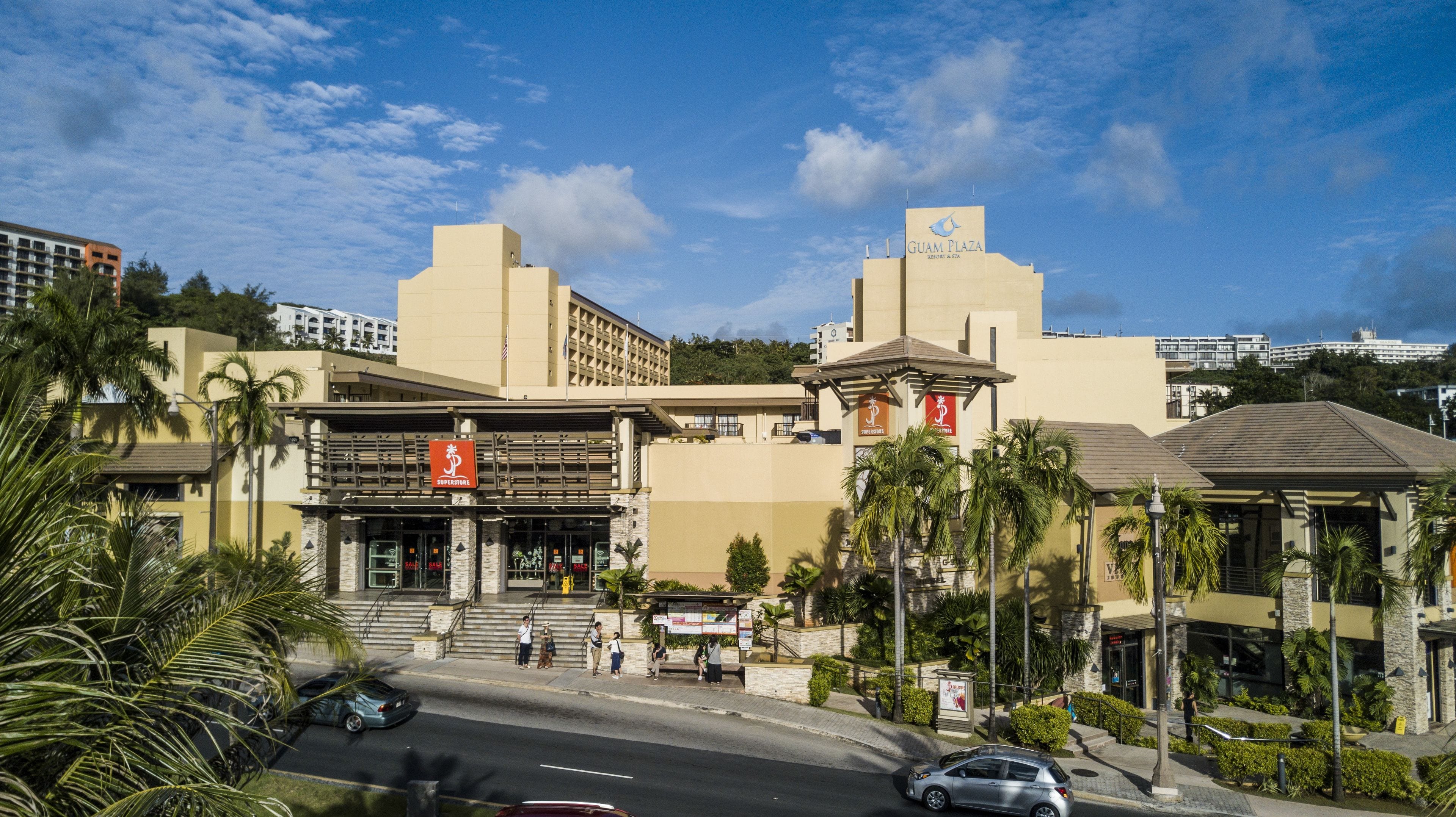 A hotel with a prominent 'Superstore' sign, a 'Guam Plaza' sign, and a 'Three Rivers' sign.