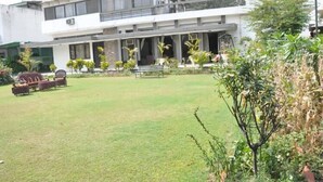A modern two-story building with a covered outdoor seating area and a well-maintained lawn. - Pulse Impulse (New Delhi)