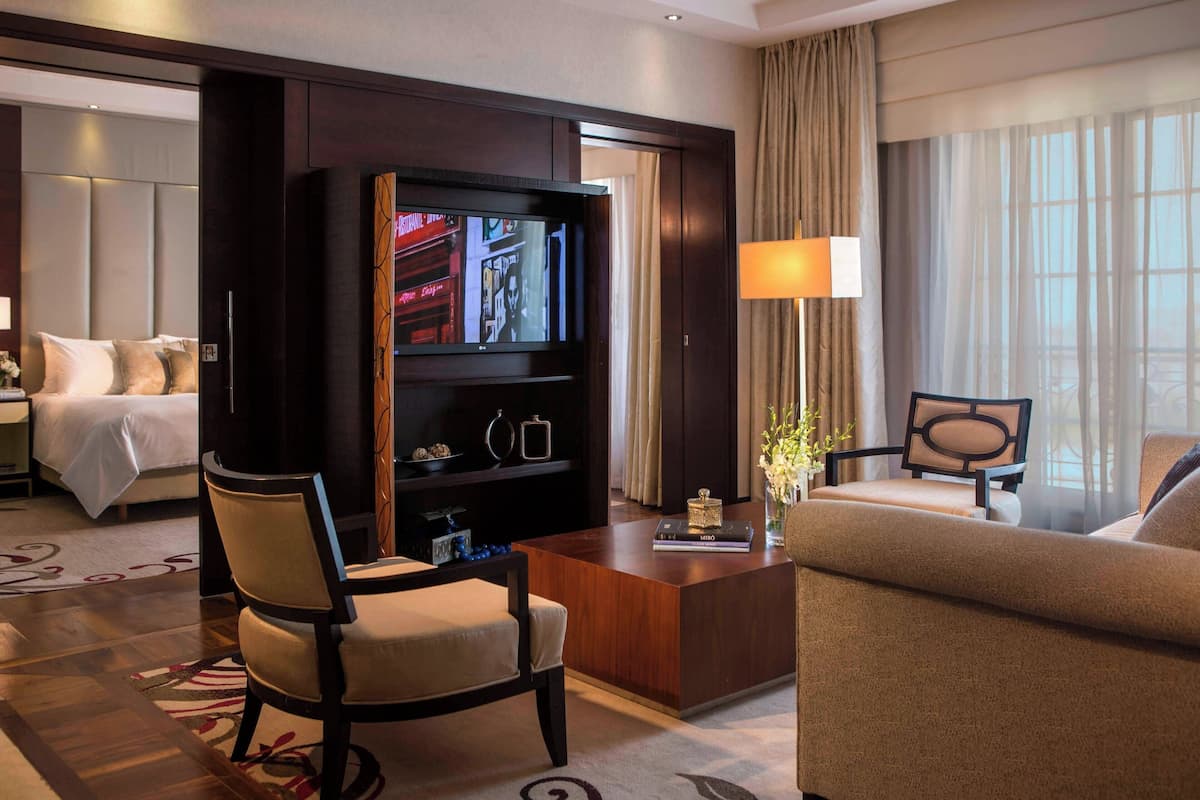 A hotel room with a bed, a TV, a desk, a chair, and a sofa.