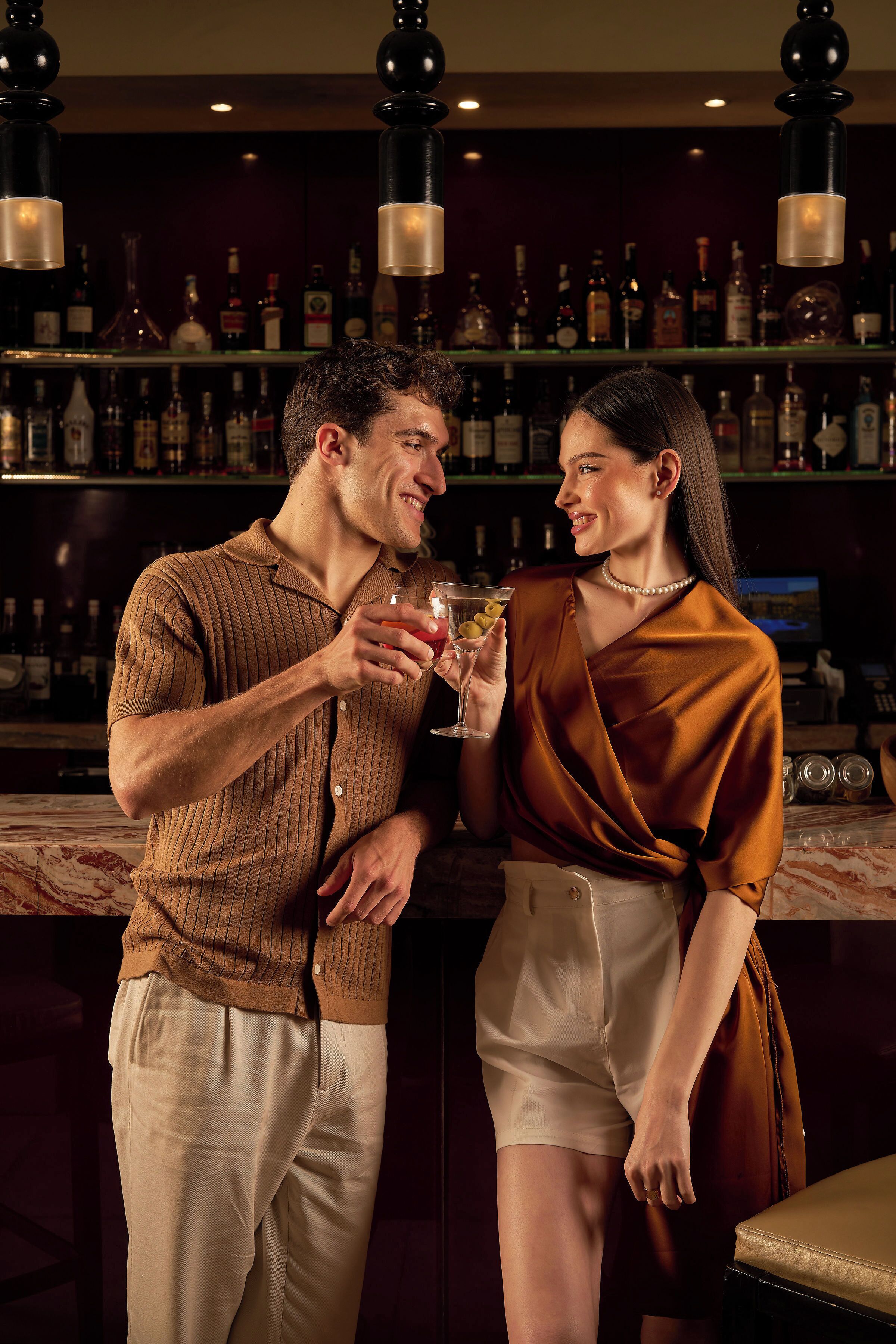 Una zona de bar con estantes llenos de botellas de licor y lámparas colgantes.