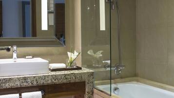 A modern bathroom with a glass-enclosed shower, a large sink, and a bathtub.