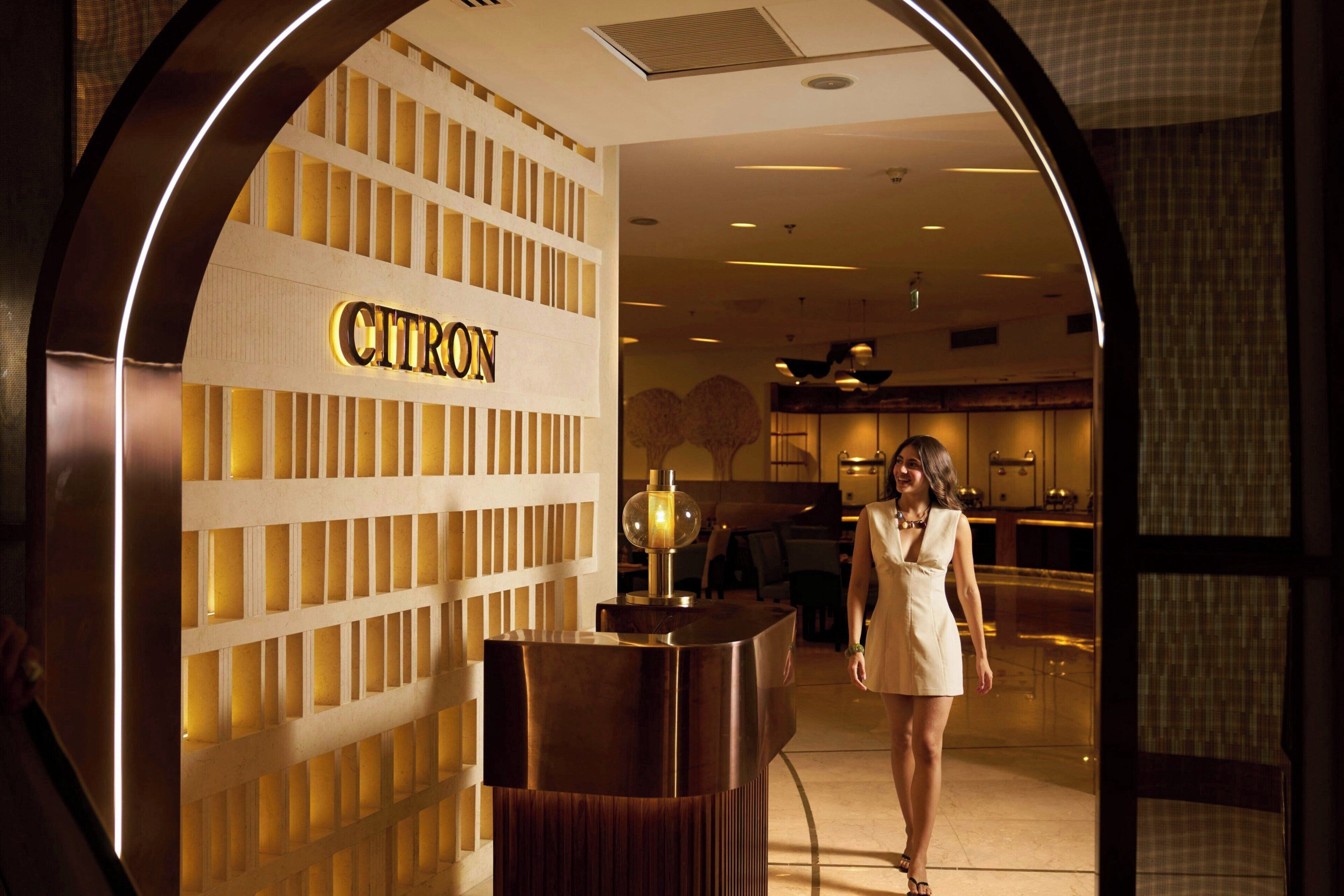 En kvinna går genom en entréhall där det finns en receptionsdisk med skylten ”CITRON”.