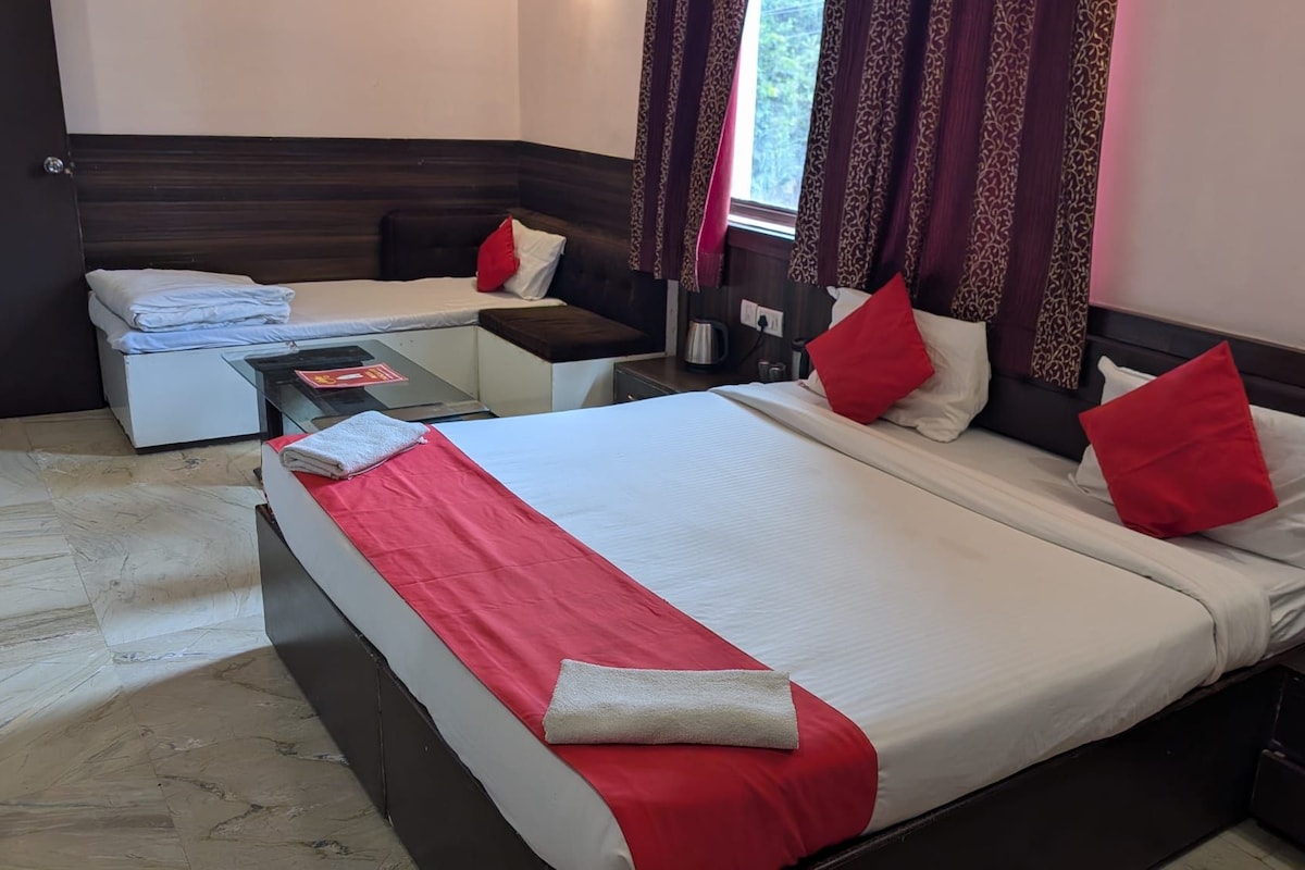 A hotel room with a large bed, a smaller bed, a desk, and a nightstand.