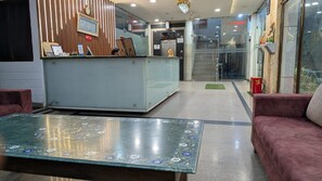 Zona de recepción con mostrador, sofá y una mesa decorativa.