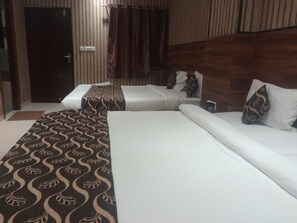 A hotel room with two beds, a patterned carpet, and a wooden headboard. - Hotel Taj Galaxy (Agra)