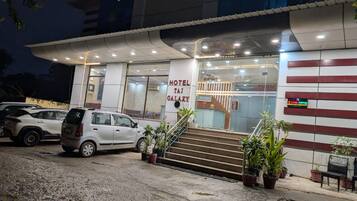 A hotel entrance with a sign reading 'HOTEL TAI GALAXY,' a staircase leading to the entrance, and a parked car.