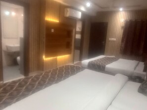 A hotel room with two beds, a bathroom, and a mirror. - Hotel Taj Galaxy  (Agra)