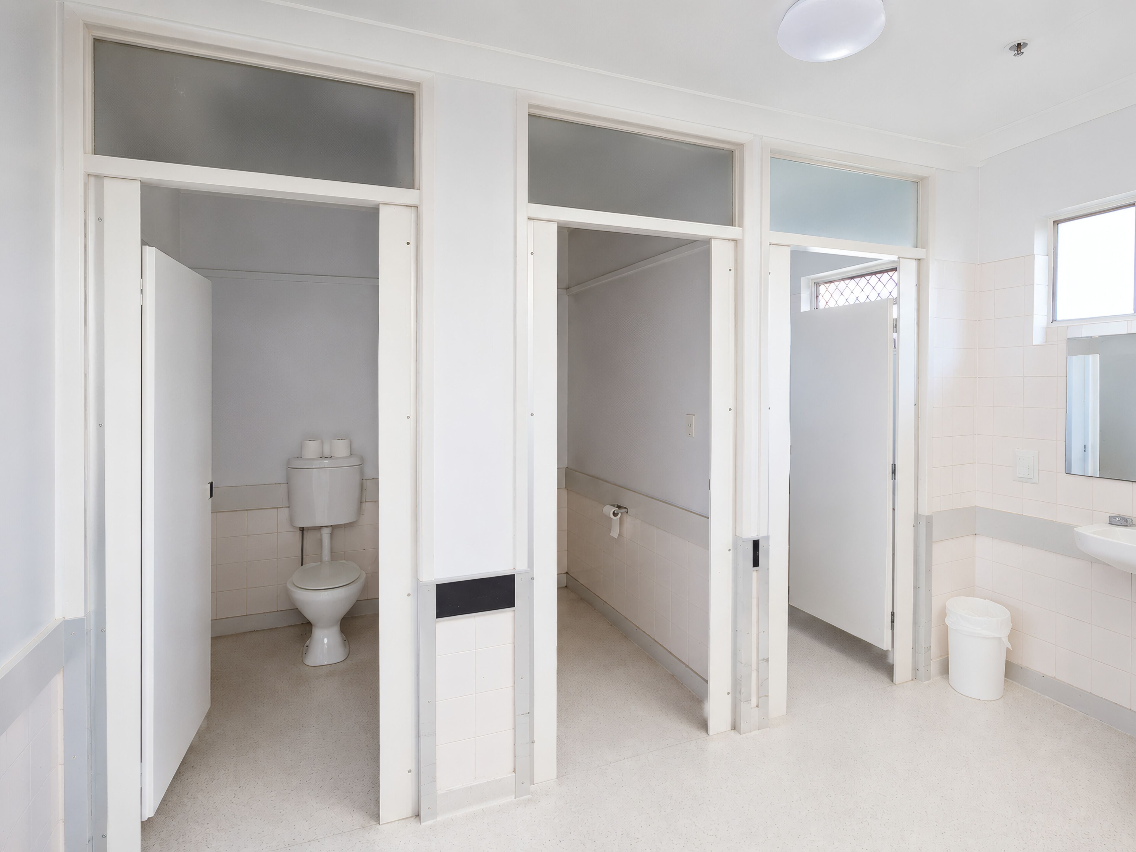 Et badeværelse med toilet, håndvask og spejl.