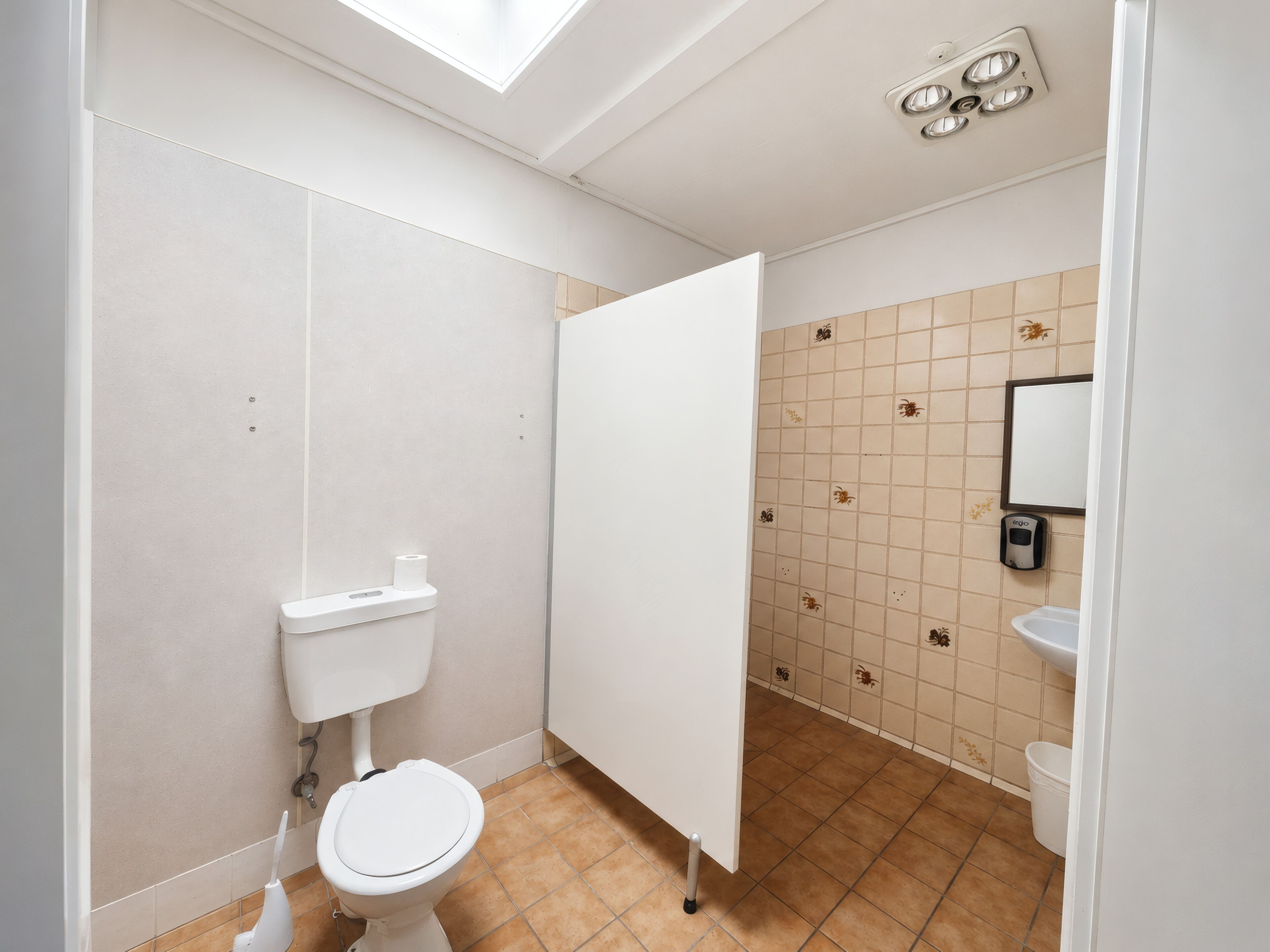 Un baño con inodoro, cabina de ducha, lavabo y espejo.