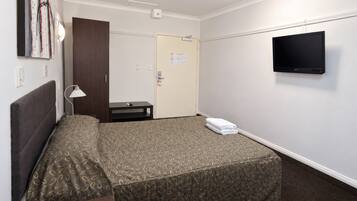 Een hotelkamer met een bed, een televisie, een bureau en een deur.