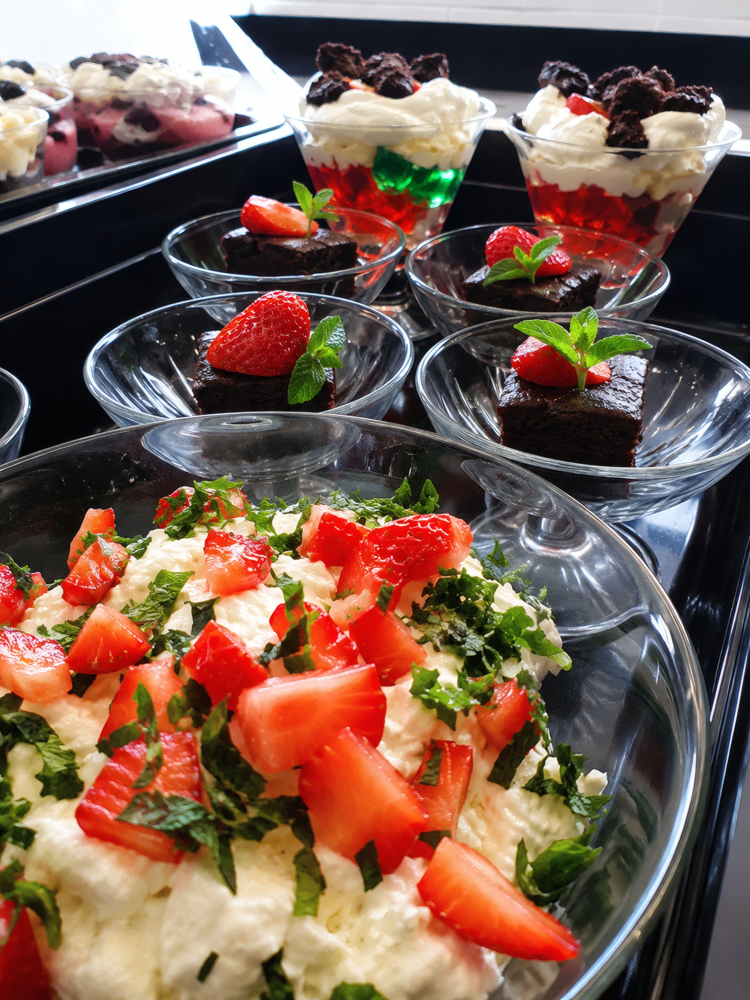 A variety of desserts including a strawberry and mint salad, chocolate desserts, and layered parfaits.