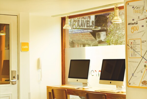 A café with two desktop computers, a wooden desk, and a map on the wall.