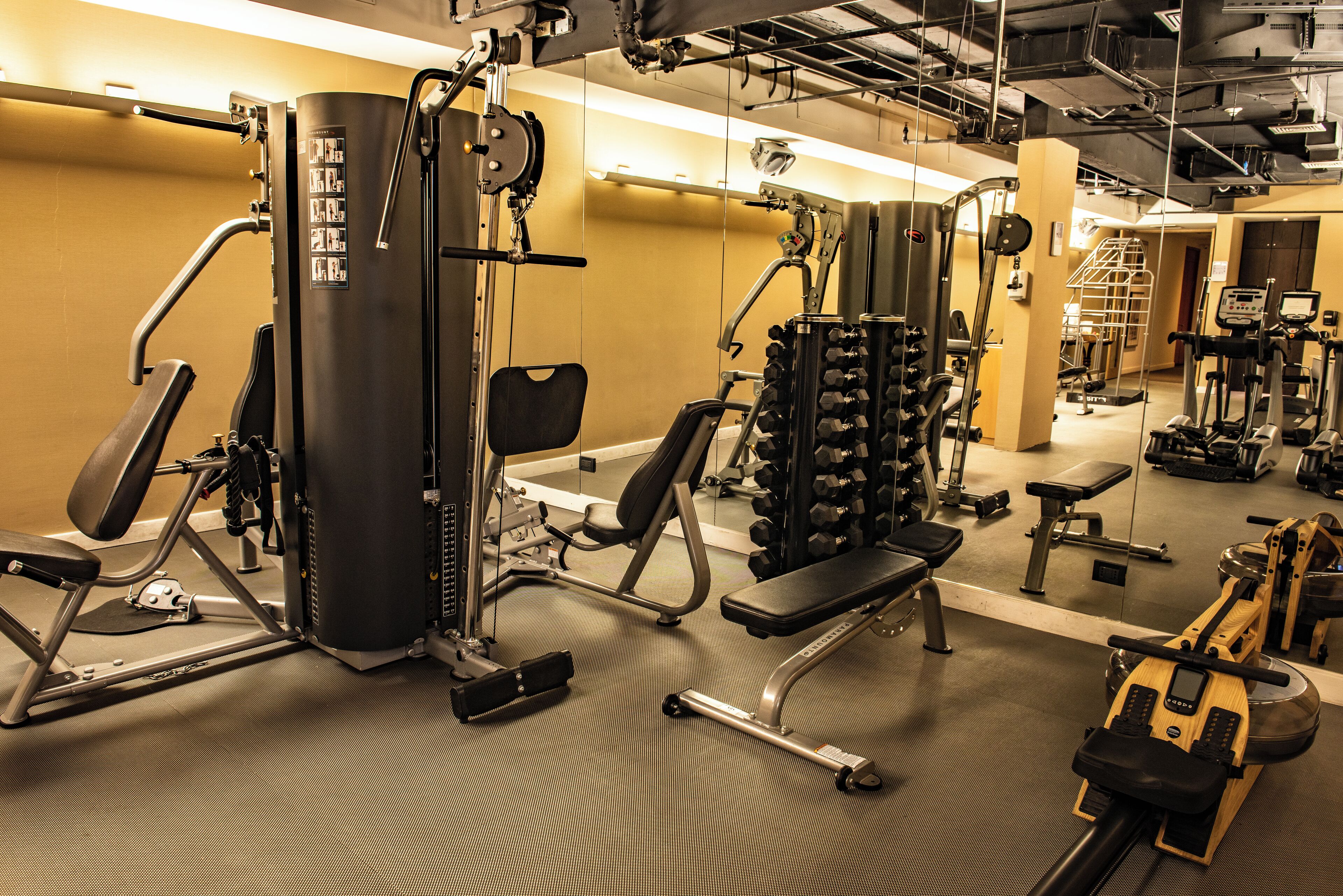 A gym with various exercise equipment including a treadmill, weight machines, and free weights.