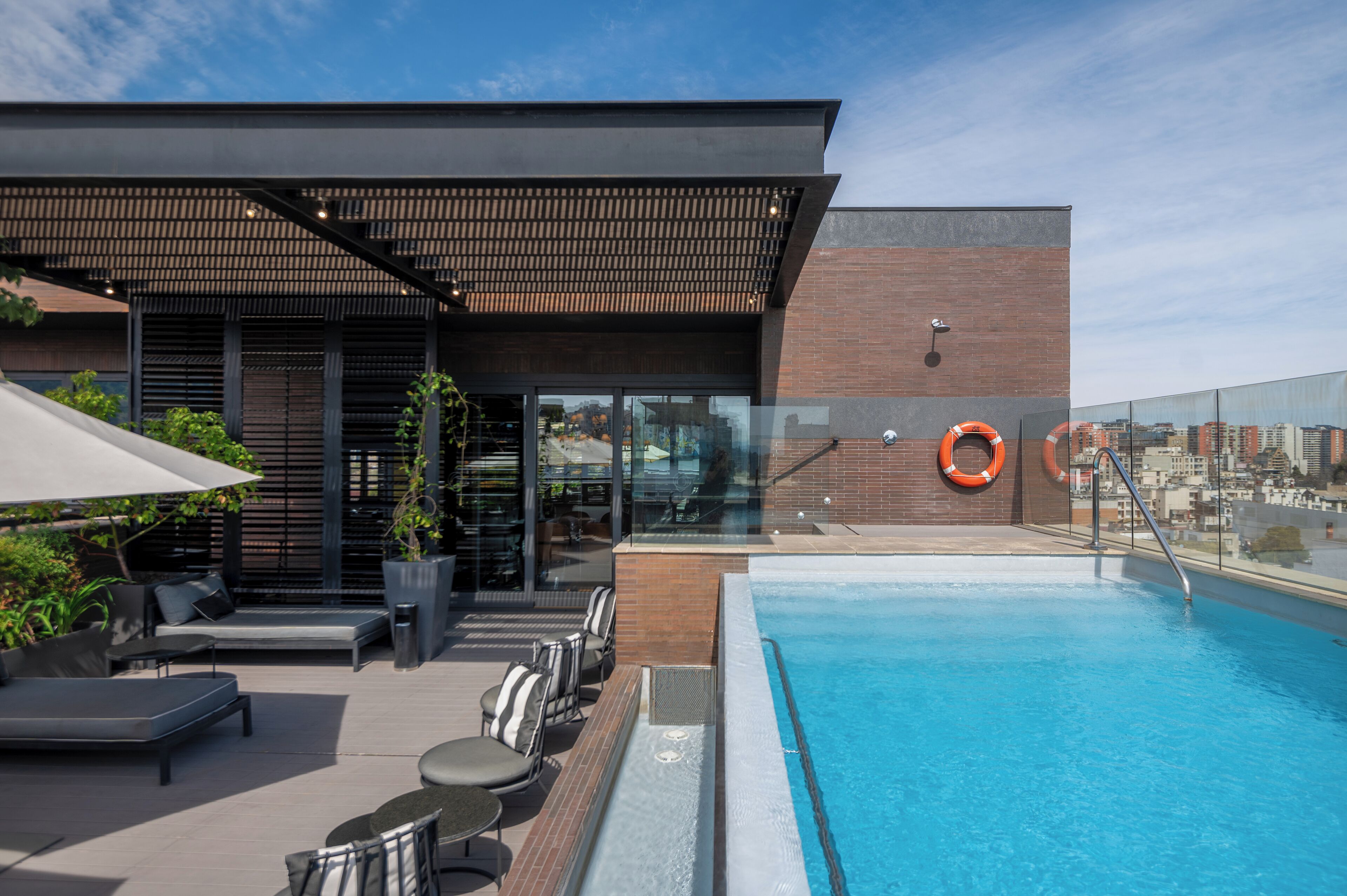 Ett poolområde på taket med en modern design, inklusive en pool, bekväma sittplatser och en täckt uteplats.