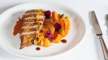 Un plato con pato en rodajas, gajos de naranja y bayas.