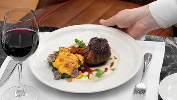 A plate of food with a glass of red wine on a table.