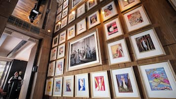 A wall with multiple framed pictures, including vintage and modern art, and a person standing near a door.