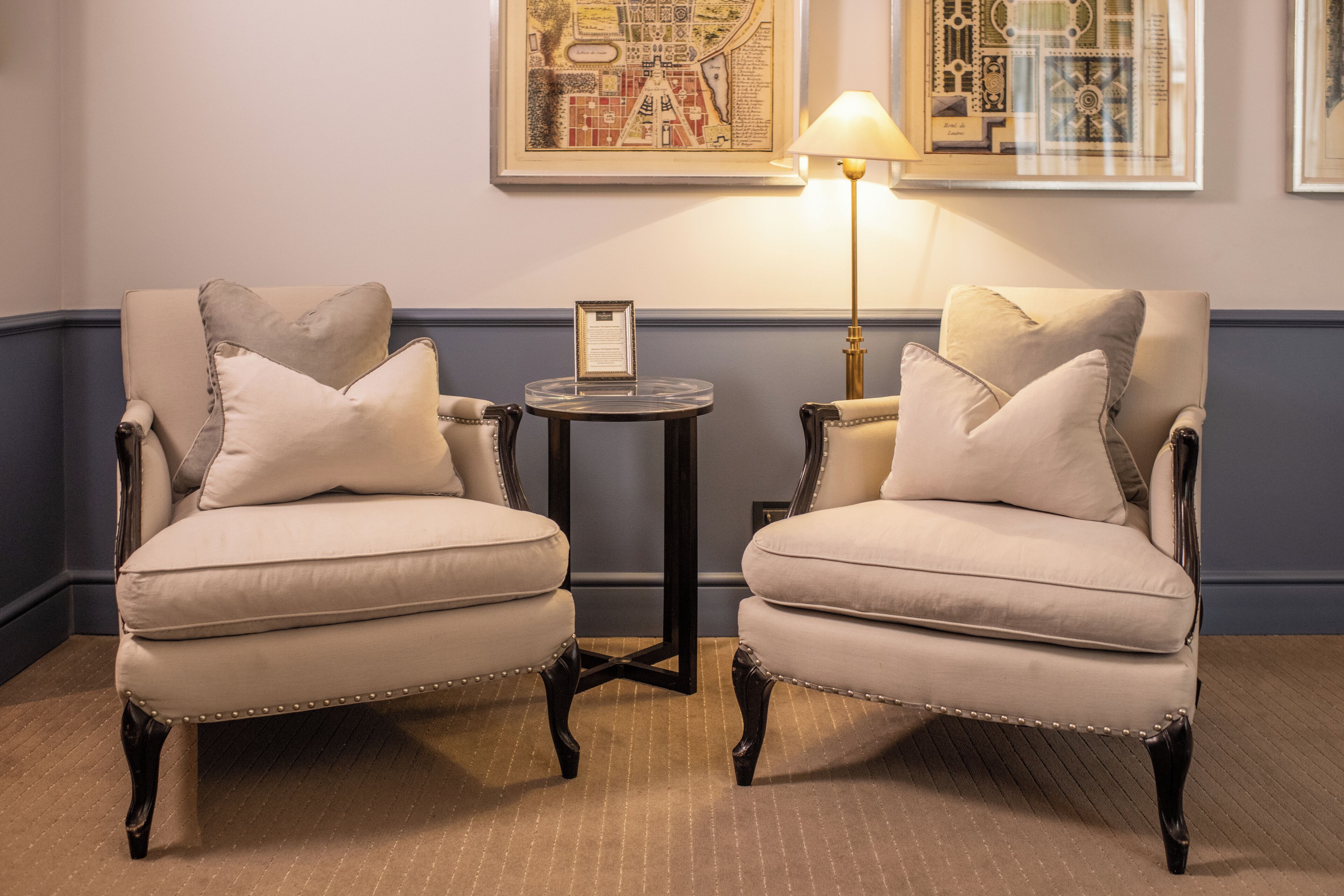 Twee fauteuils met bijpassende kussens en een salontafel met een lamp ertussen.