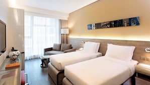 A hotel room with two beds, a sofa, a TV, and a lamp. - Lodgewood by Nina Hospitality丨Mong Kok (Kowloon)