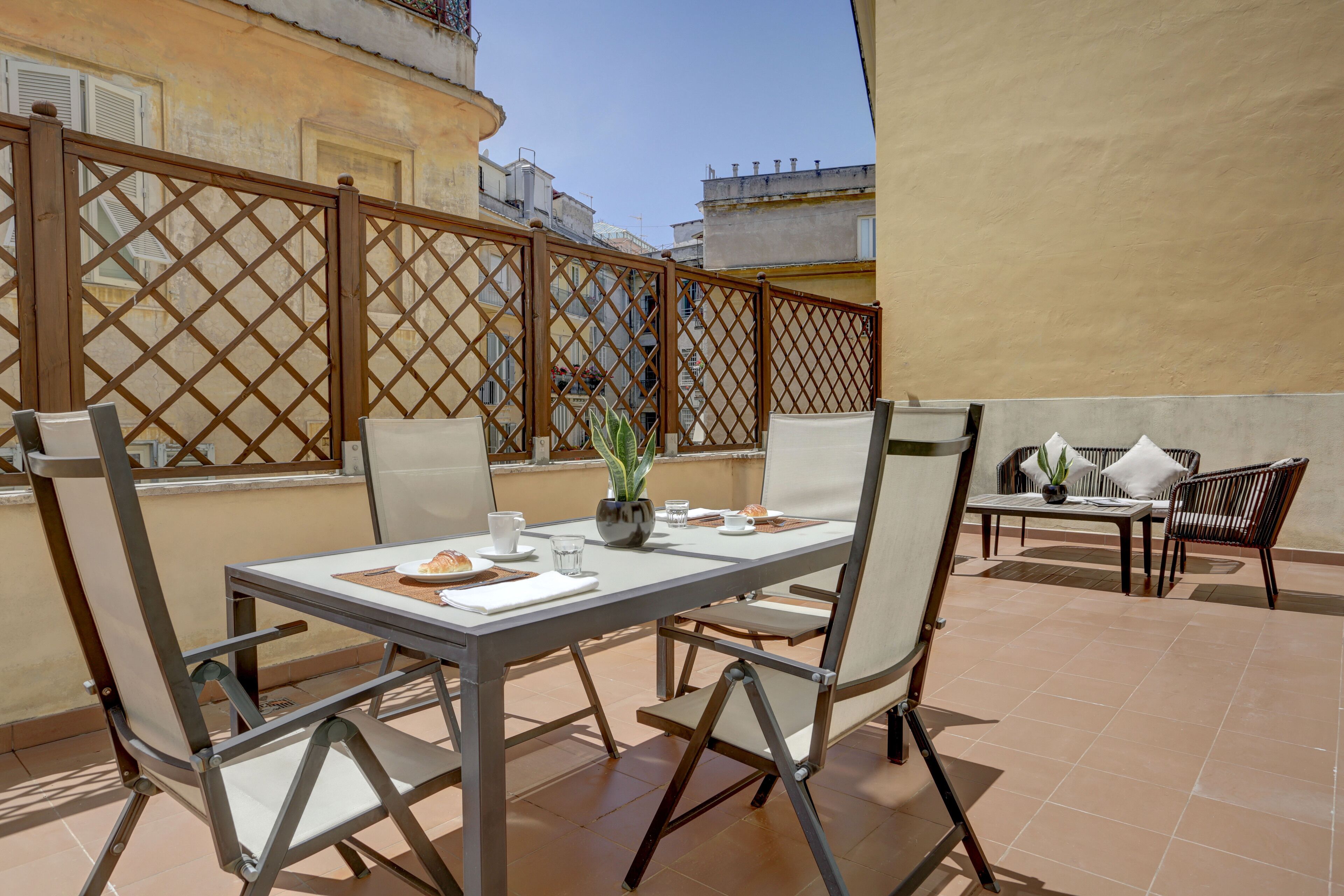 A patio with a table and chairs, a potted plant, and a whiteboard.