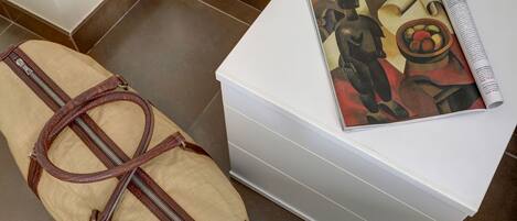 Una bolsa de lona color beige con una correa marrón y una caja de almacenamiento blanca con una revista encima.
