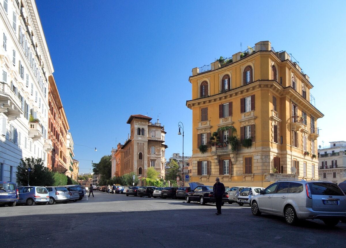 A street with parked cars and historic buildings.