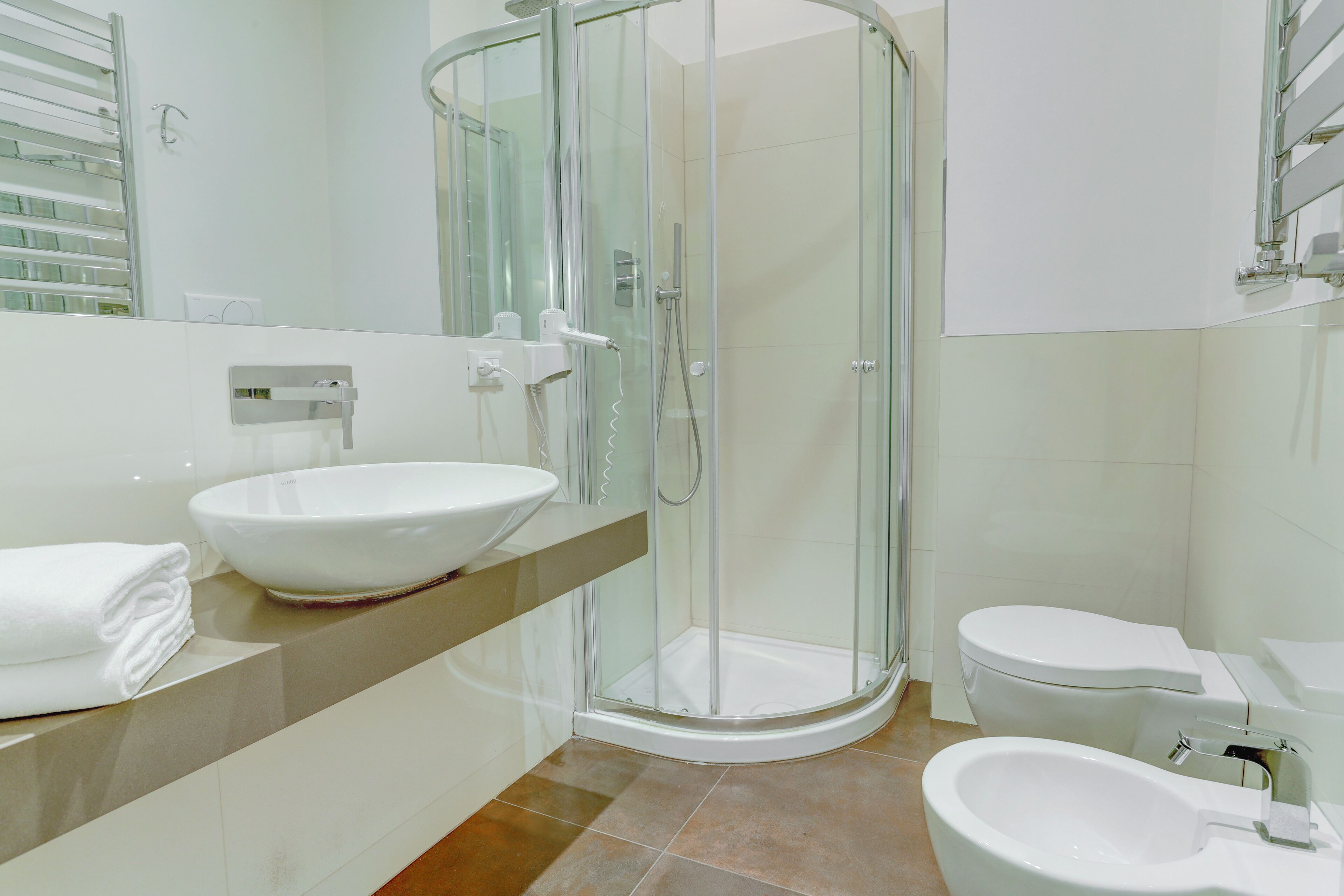 A modern bathroom with a glass-enclosed shower, a white sink, and a toilet.