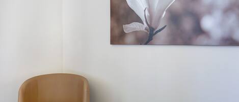 Una silla en una habitación con un cuadro de una flor de magnolia colgado en la pared.