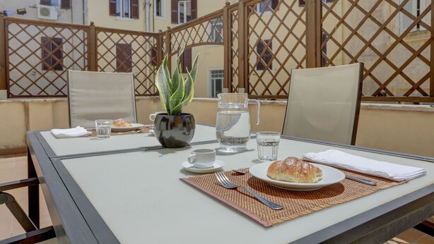A table set for two with a croissant, a glass of water, a cup, and a potted plant. - Colosseo Gardens - My Extra Home (Rome)