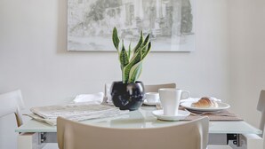 A dining table with a potted plant, a croissant, and newspapers. - Colosseo Gardens - My Extra Home (Rome)