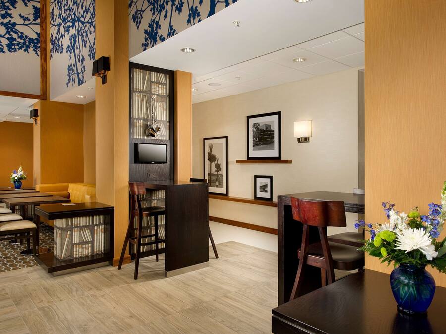 A hotel lobby with a reception desk, seating area, and a TV mounted on the wall.