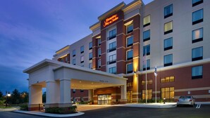 Ein Hampton Inn & Suites mit moderner Fassade, großen Fenstern und einem gut beleuchteten Eingang.